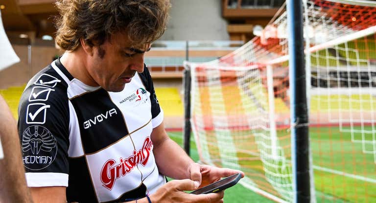 Fernando Alonso consulta el móvil durante un partido de fútbol benéfico en 2022.