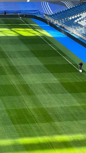 Imagen de un operario pintando las nuevas líneas del nuevo césped del Bernabéu.  Relevo
