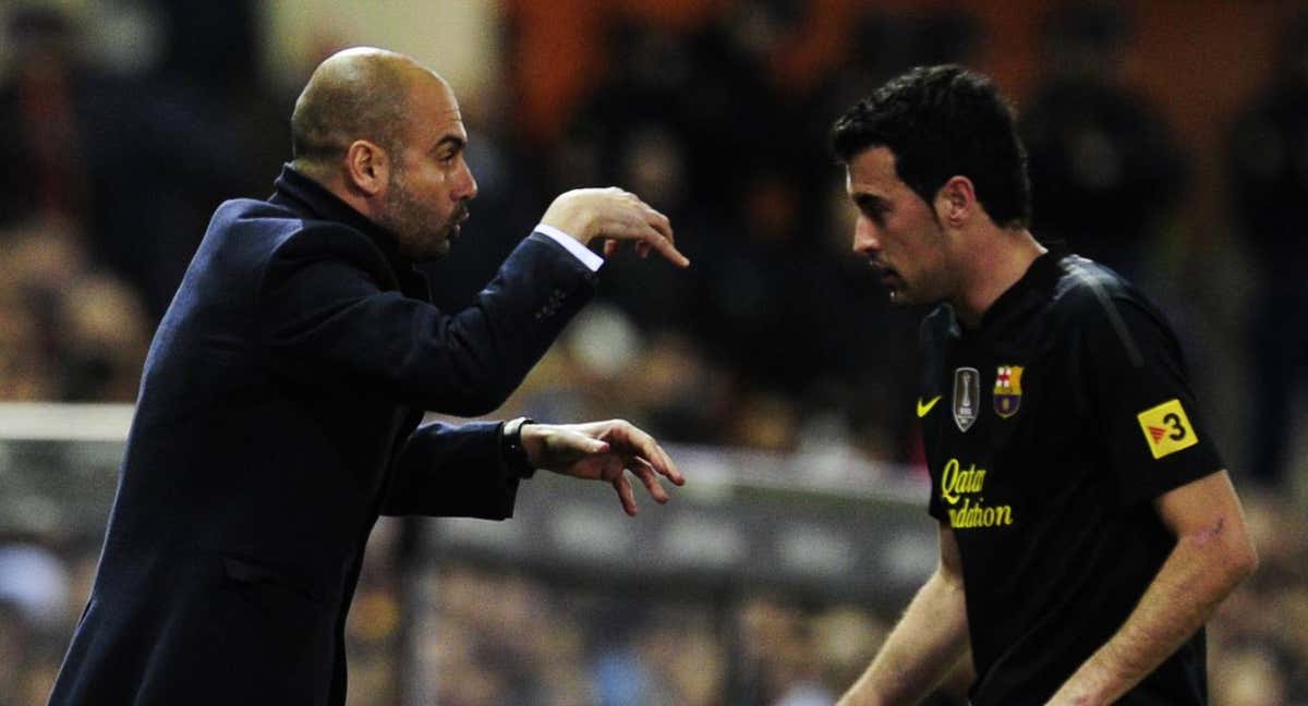 Guardiola le da instrucciones a Busquets durante un partido.