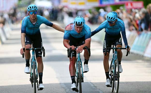 Dos compañeros de Astana ayudan a Syritsa a entrar en la meta tras la caída.  Getty.