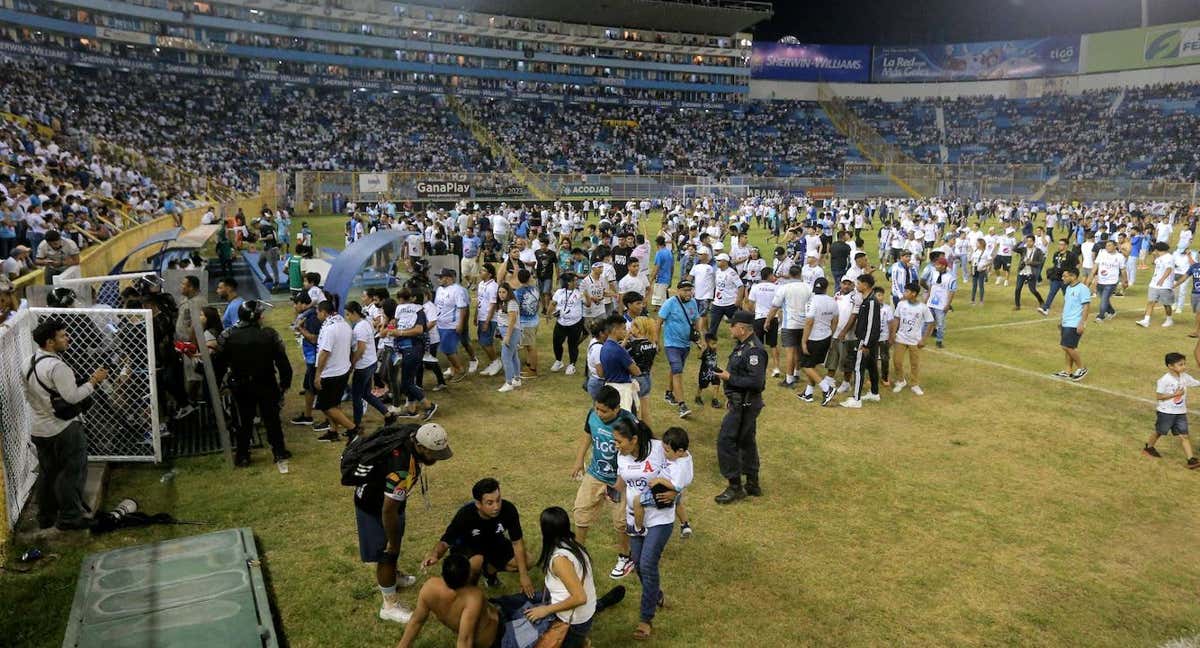 Varios aficionados son atendidos sobre el césped del estadio.