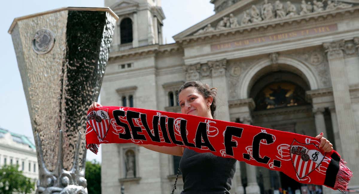 Una aficionada del Sevilla posa junto al trofeo de la Europa League./Reuters