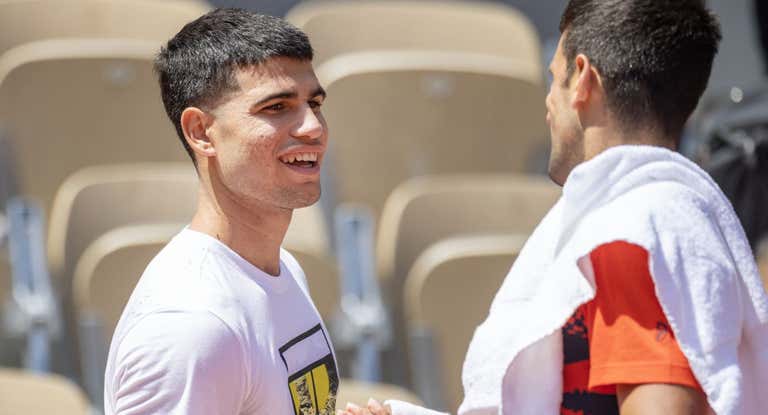 Alcaraz y Novak Djokovic se saludan durante un entrenamiento en Roland Garros.