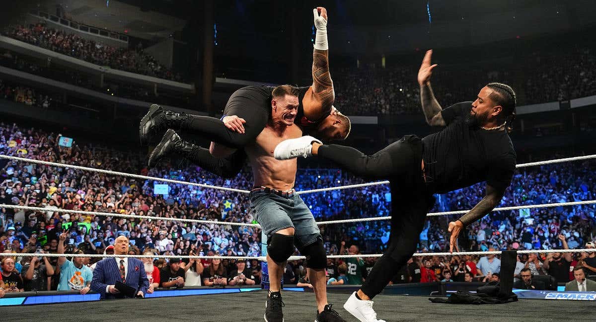 John Cena recibe una patada de Jimmy Uso mientras carga con Solo Sikoa.