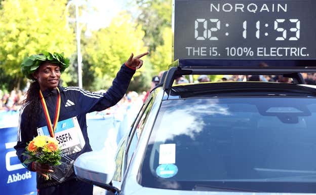 Assefa posa junto a la marca del nuevo récord mundial de maratón. REUTERS
