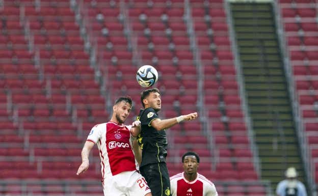 Santiago Giménez (camiseta negra) pelea un balón con van den Boomen, jugador del Ajax. EFE