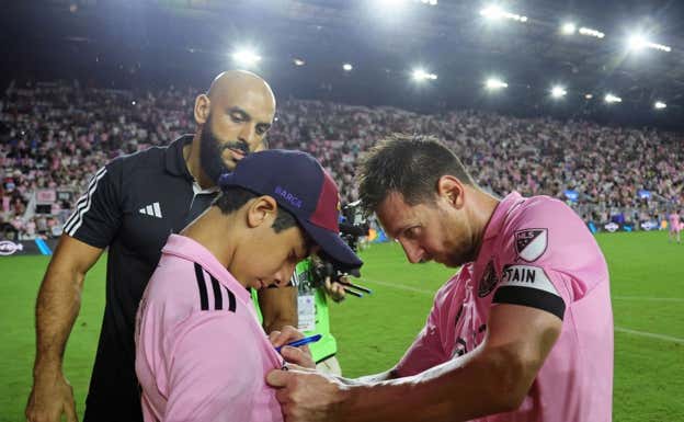 Messi firma un autógrafo a un fan que se coló en el campo.  REUTERS