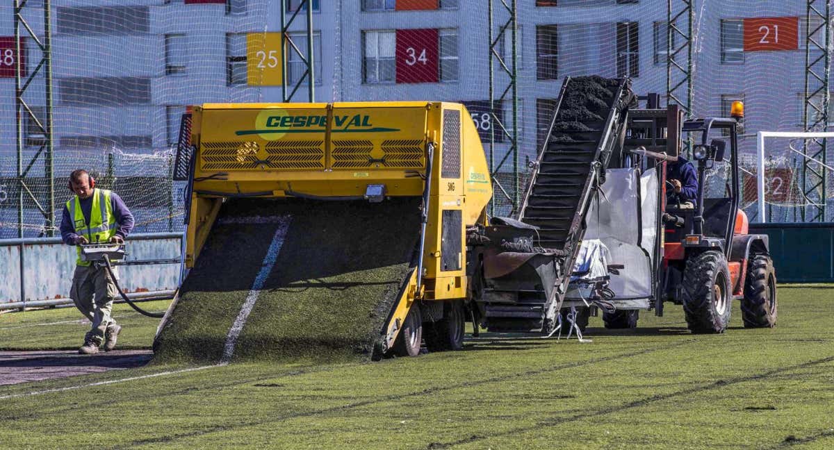 Unos operarios retiran las planchas de césped artificial en la ciudad deportiva del Racing de Santander en 2017.