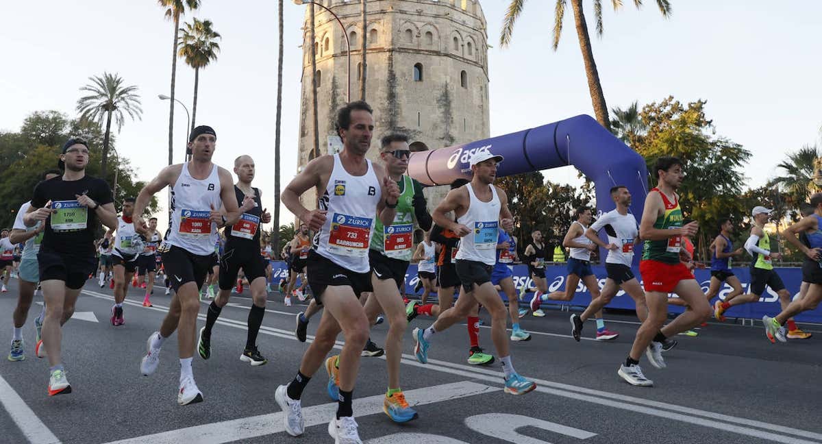 Los atletas pasan por la Torre del Oro durante el maratón de Sevilla./EFE