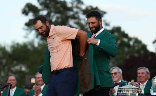 Jon Rahm pone la chaqueta verde a Scottie Scheffler. AFP