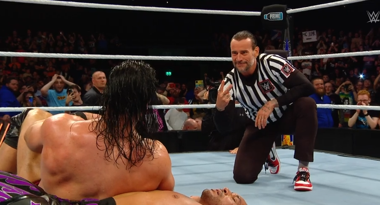 CM Punk indica a Drew McIntyre el resultado del conteo.