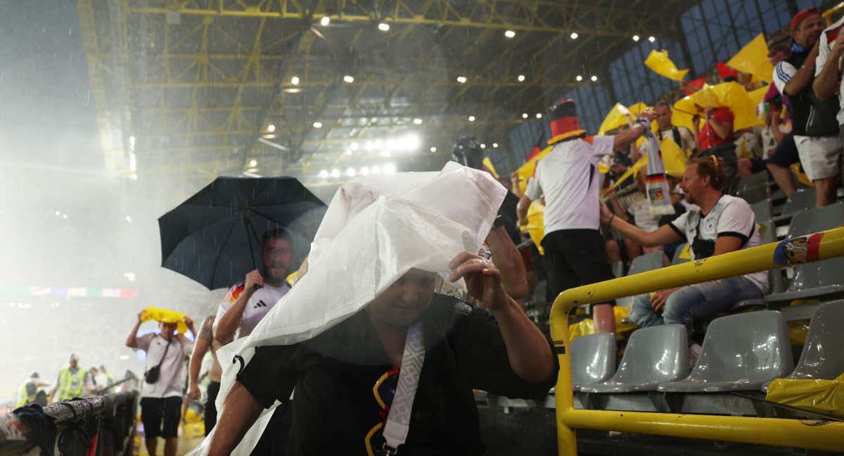 Aficionados se protegen en medio de la tormenta eléctrica que provocó la suspensión en Dortmund del Alemania-Dinamarca. /GETTY