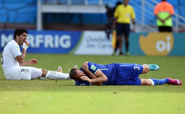 Suárez y Chiellini en el suelo instantes después del mordisco. AFP