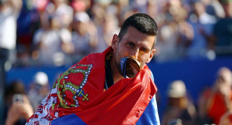 Novak Djokovic besa la medalla olímpica de oro envuelto en la bandera de Serbia.